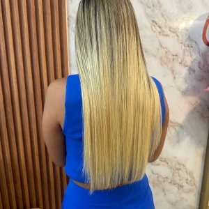 22-inch balayage hair extensions with a natural blend of dark brown roots transitioning to blonde. High-quality, smooth, and silky texture with adhesive application.