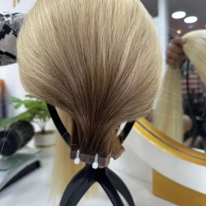 22-inch balayage hair extensions with a natural blend of dark brown roots transitioning to blonde. High-quality, smooth, and silky texture with adhesive application.