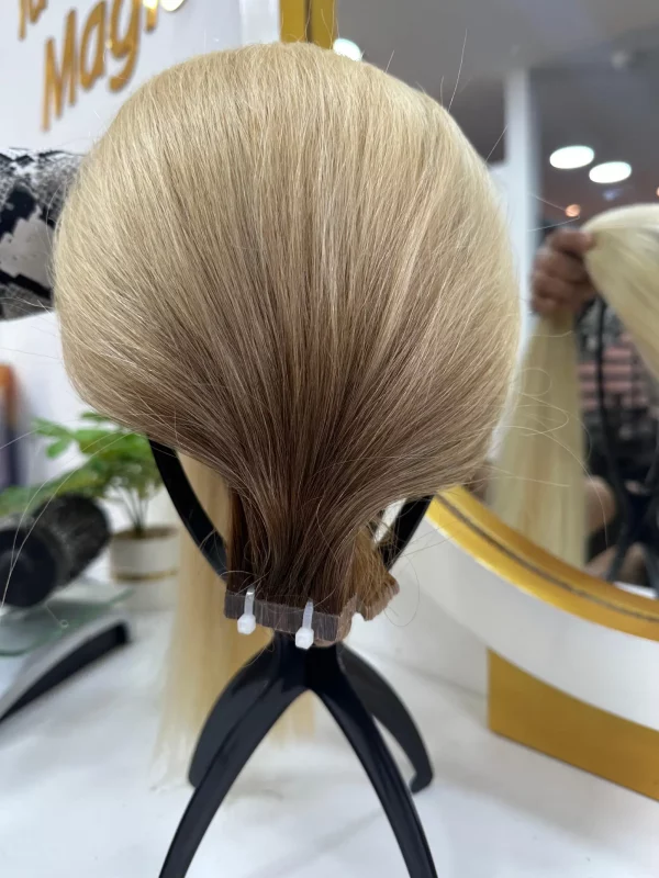 22-inch balayage hair extensions with a natural blend of dark brown roots transitioning to blonde. High-quality, smooth, and silky texture with adhesive application.