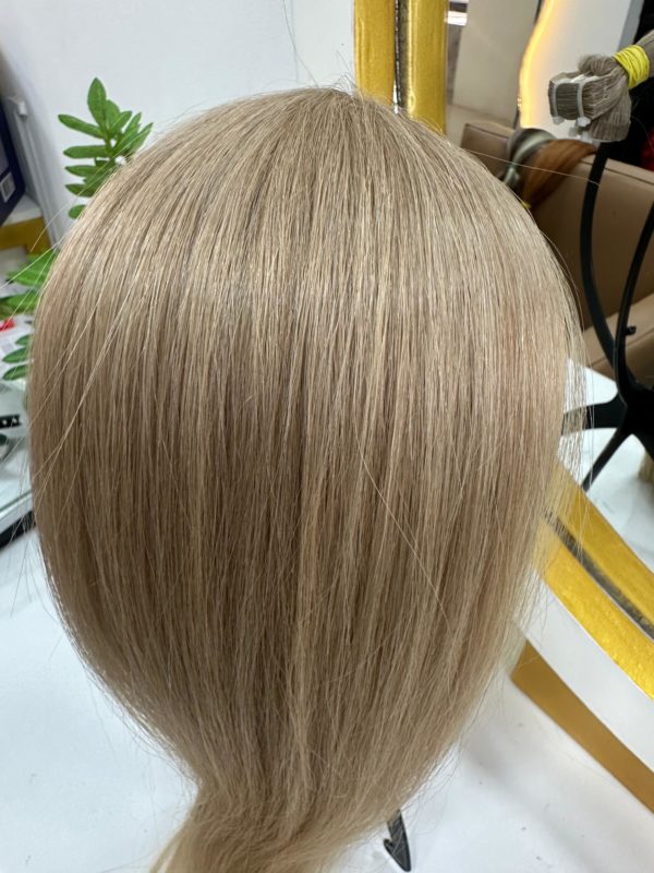 A close-up of smooth, straight, and silky Color 18M blonde hair extensions displayed on a mannequin head, reflecting a natural shine in a salon setting.