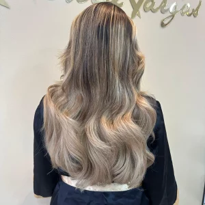 A close-up of smooth, straight, and silky Color 18M blonde hair extensions displayed on a mannequin head, reflecting a natural shine in a salon setting.