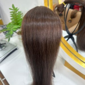 A bundle of straight, silky Color 2 hair extensions displayed on a mannequin head in front of a mirror. The rich brunette shade is smooth and glossy.