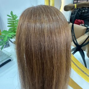 High-quality Color 4 hair extensions in a warm brown shade, styled straight with a natural shine, displayed in a salon setting with a mirror and greenery.