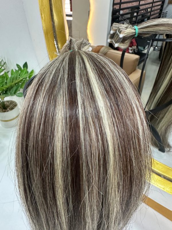 High-quality Color 4/22 hair extensions featuring a blend of warm brown and blonde highlights. The extensions are bundled and displayed in a salon setting.