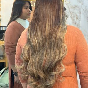 High-quality Color 4/22 hair extensions featuring a blend of warm brown and blonde highlights. The extensions are bundled and displayed in a salon setting.
