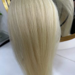 Color 60 blonde hair extensions – A close-up image of silky, straight, platinum blonde (Color 60) hair extensions displayed on a stand with a mirror in the background.